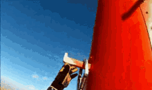 a person wearing gloves is painting a red object with a brush