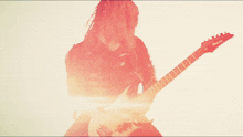 a man playing an ibanez electric guitar in a red light