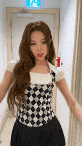 a woman wearing a plaid top and a black skirt