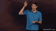a man in a blue shirt is waving at the camera .