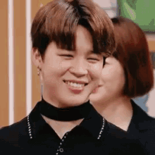 a close up of a person wearing a choker and smiling with a woman in the background .