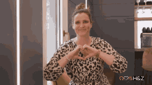 a woman in a leopard print dress is making a heart with her hands