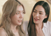 two women are smiling and looking at each other with a yellow background behind them that says thailand