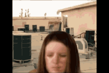 a woman is standing on a rooftop with her eyes closed