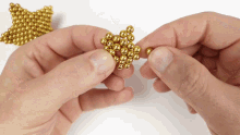 a person is holding a pile of gold beads in their hands