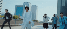 a group of people are dancing in front of a building that says aoi