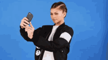 a woman wearing a black jacket is taking a selfie with her phone .