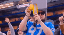 a man wearing a blue jersey with the number 97 on it is holding a bottle of ketchup .