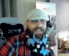 a man wearing a plaid shirt and a white hat is talking on a cellphone