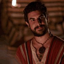 a man with a beard is wearing a necklace with a pendant on it