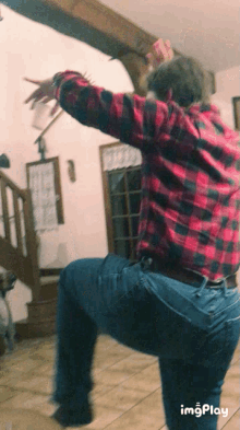 a man in a plaid shirt is standing on one leg in a living room
