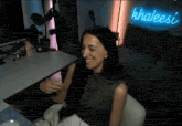 a woman is sitting in a chair in front of a neon sign that says khaleesi .