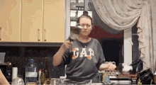 a woman in a gap shirt is pouring a bottle of wine into a glass .