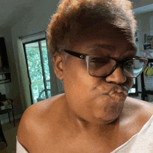 a woman wearing glasses makes a funny face in front of a sign that says no dogs
