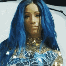 a woman with blue hair is wearing a gold top with rhinestones .