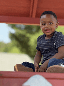 a young boy wearing a striped shirt with the letter l on the front