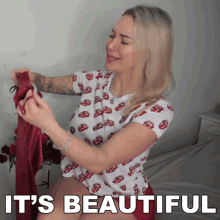 a woman in a rolling stones shirt is holding a red item with the words it 's beautiful below her