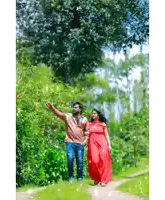 a man and a woman are walking down a path in the woods holding hands