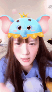 a girl wearing a blue dumbo hat with a crown on top