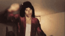 a man is dancing in a room wearing a wig and a jacket .