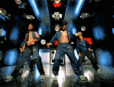 a group of men are dancing in a dark room with blue lights