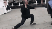 a man is doing a karate move on a sidewalk .