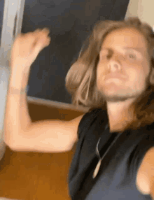 a man with long hair is wearing a black shirt