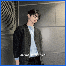 a man wearing glasses and a sweater with the words somos de emi > l < below him