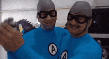 two men in superhero costumes with the letter a on their shirts