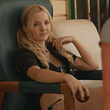 a woman sits in a chair with her arm resting on the arm rest of the chair