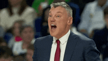 a man in a suit and tie is shouting during a basketball game