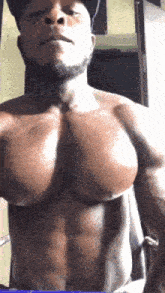 a man without a shirt is taking a selfie with his huge muscles .