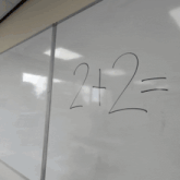 a man is writing on a white board with a marker and the number 2 is written on it