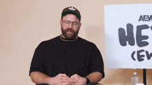 a man sitting in front of a sign that says " he 's "