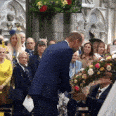 a man in a blue suit holds a bouquet of flowers