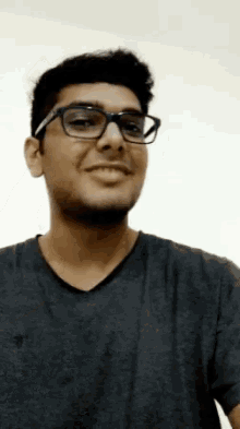 a man wearing glasses and a black shirt is smiling .