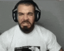 a man with a beard is wearing headphones and a white shirt .