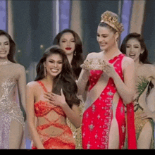 a group of women are standing next to each other on a stage and one of them is wearing a crown .