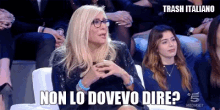 a woman wearing glasses is sitting in front of a crowd and says non lo dovevo dire
