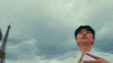 a man stands in front of a cloudy sky with his hands on his chin