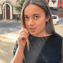 a woman in a black shirt is standing on a sidewalk in front of a store that says ' olivia vera '