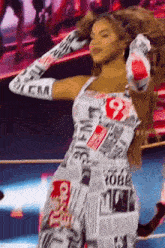 a woman is wearing a newspaper dress and gloves while dancing on a stage .