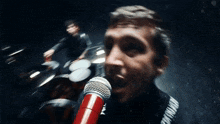 a man singing into a red microphone with the word twenty one pilots on his chest