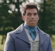 a man wearing a blue coat and a blue tie is making a funny face .