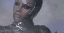 a woman in a futuristic costume with a helmet on her head is looking at the camera .