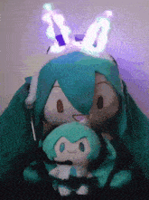a stuffed hatsune miku sitting next to a stuffed hatsune miku