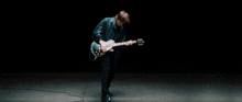 a man in a black shirt is playing a guitar in the dark