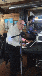 a man playing a keyboard in front of a microphone that says yamaha on it