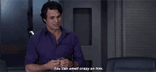 a man in a purple shirt is sitting in a chair and talking to someone .