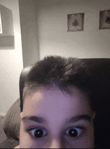 a close up of a person 's face with a picture on the wall behind him
